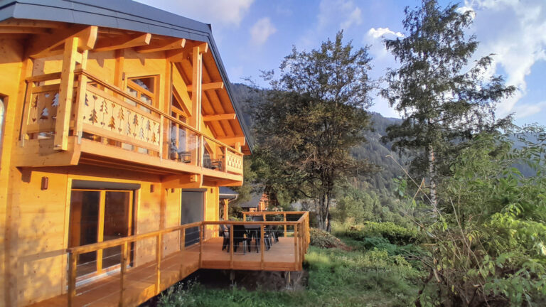 Façade du chalet La Godille, avec balcon, terrasse, vue sur les montagnes, entouré par la forêt. Location en Savoie, Val d'Arly.