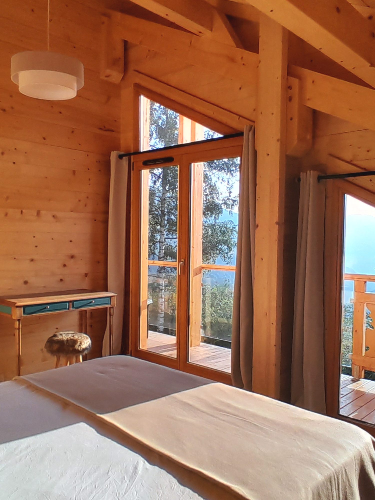 Chambre de l'étage du chalet La Godille, location à la semaine, avec balcon et vue sur les montagnes.