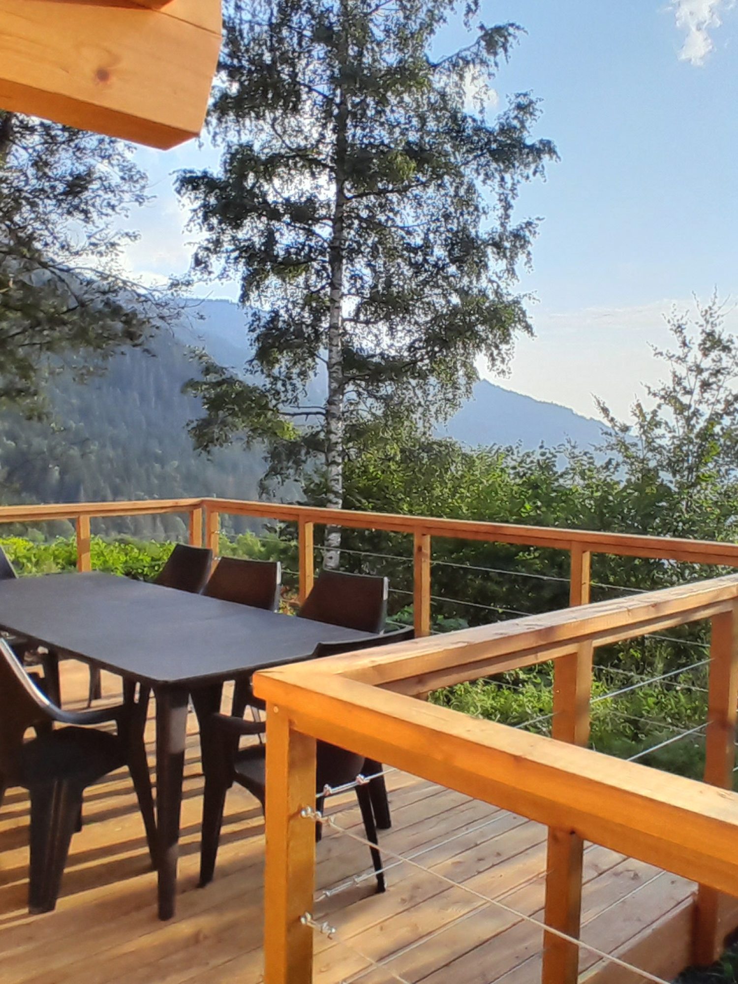 La terrasse en bois, ensoleillée, du chalet La Godille, location en Savoie, avec vue sur le Val d'Arly.