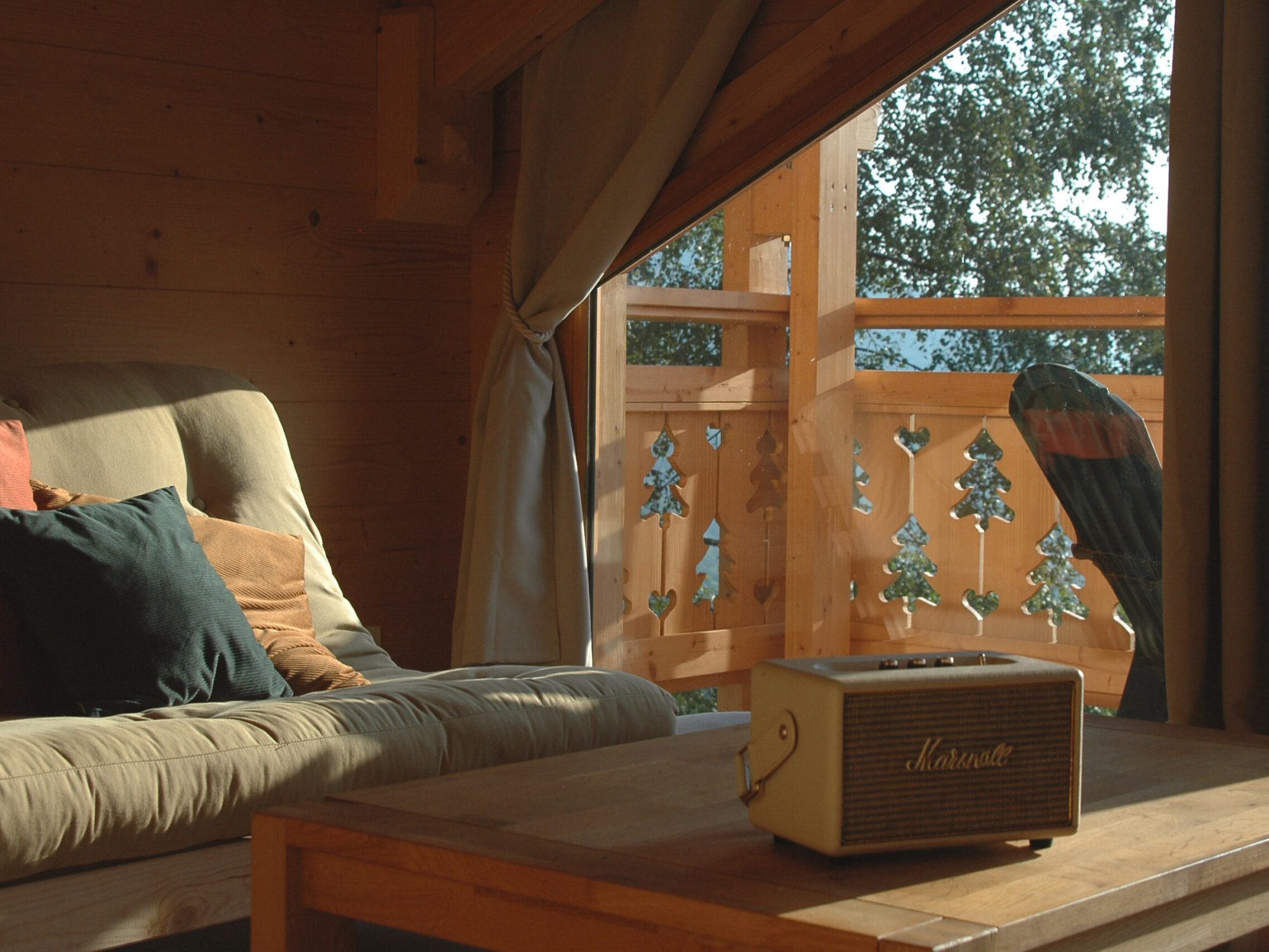 Salon du chalet La Godille, location en Savoie, avec canapé, fauteuils, enceinte Marshall et mobilier en bois.