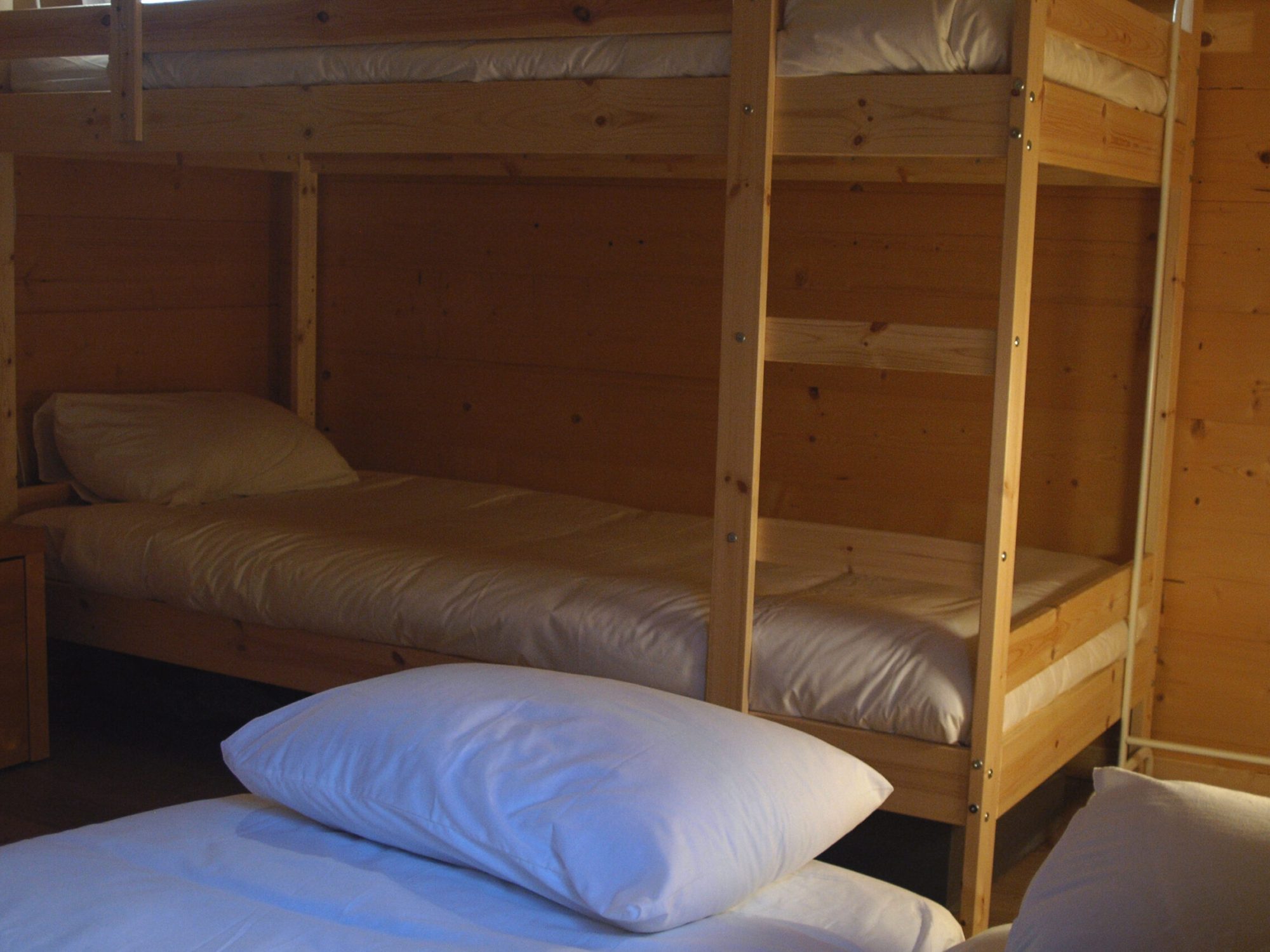 Dortoir avec 4 lits dont 2 lits superposés au chalet La Godille, location en Savoie. Mobilier et murs en bois, lits confortables, draps fournis.